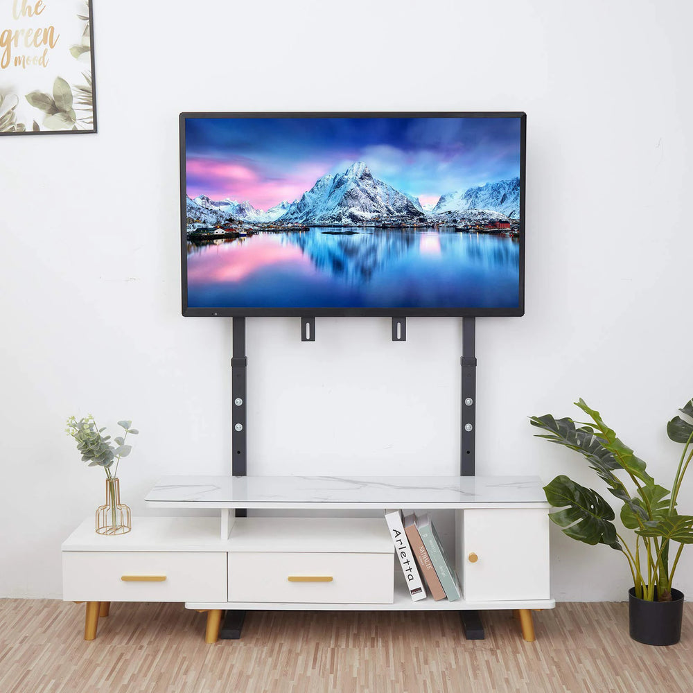 Support TV sur pied noir installé derrière un meuble TV blanc