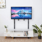 Support TV sur pied noir installé derrière un meuble TV blanc
