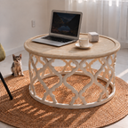Table basse ronde Sivra avec plateau bois naturel et piètement ajouré blanc sur fond clair.